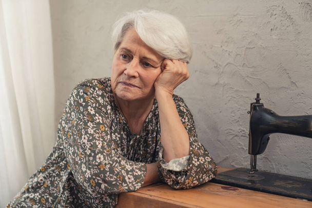 lonely European elderly lady thinking about sad things and touching her grey hair  - Photo, Image