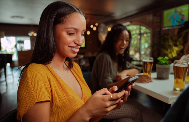 afroamericana hembra fuera para bebidas mensajes de texto en el teléfono móvil  - Foto, Imagen