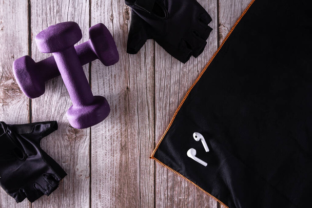 Mancuernas de fitness púrpura con guantes deportivos y auriculares. Accesorios de gimnasio. Copiar espacio. Enfoque selectivo. - Foto, imagen