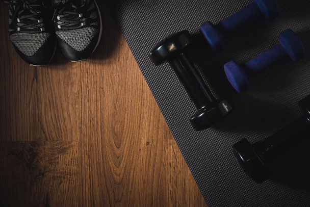 Dumbbells for fitness on mat and sneakers. Gym accessories. Copy space. Selective focus. - 写真・画像