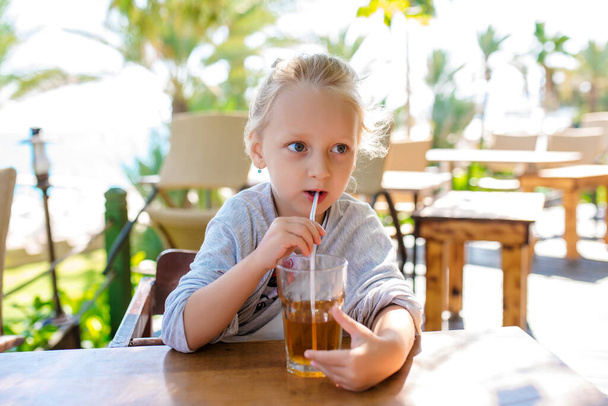Fun cute kid girl drinking healthy smoothie juice in street restaurant. Closeup toned portrait - Foto, immagini