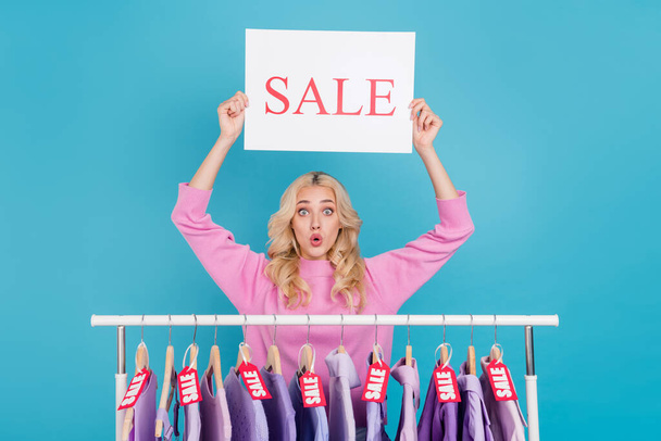 Portrait of attractive stunned wavy-haired girl holding sale poster wow outlet isolated over bright blue color background - Photo, Image