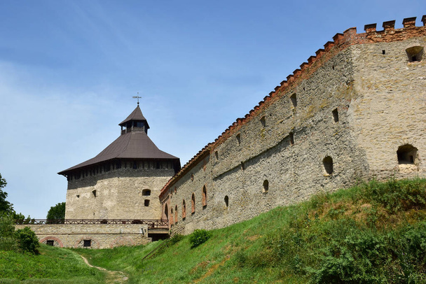 Ένα ισχυρό πέτρινο τείχος ενός μεσαιωνικού φρουρίου με πολλά παραθυράκια και πολεμίστρες - Φωτογραφία, εικόνα
