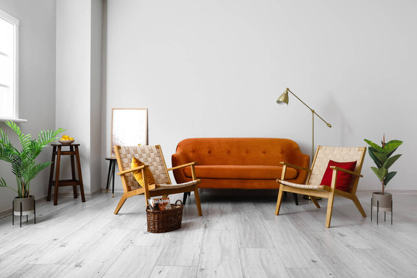 Интерьер современной гостиной с диваном и креслами возле светлой стены - Фото, изображение