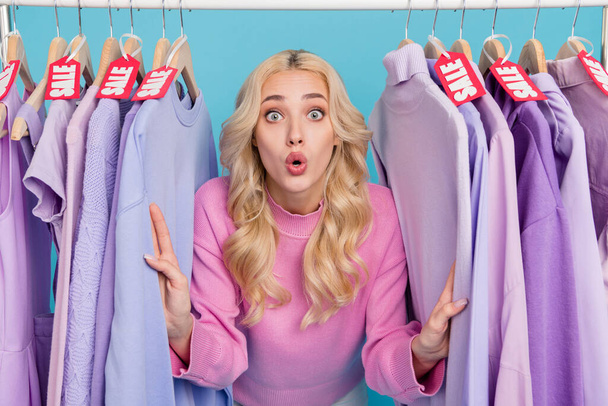 Portrait of attractive amazed wavy-haired girl choosing new wear bargain isolated over bright blue color background - Foto, immagini