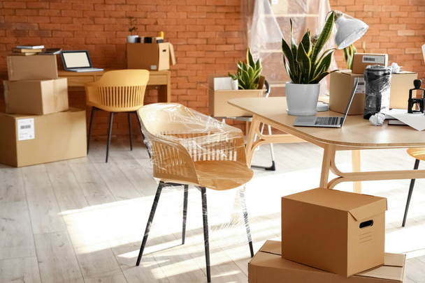 Картонные коробки с вещами и мебелью в интерьере офиса в день переезда - Фото, изображение