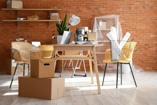 Scatole di cartone con oggetti e mobili in interni di ufficio durante giorno commovente - Foto, immagini