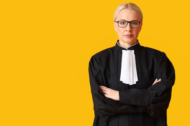 Mature female judge in robe on yellow background - Photo, image