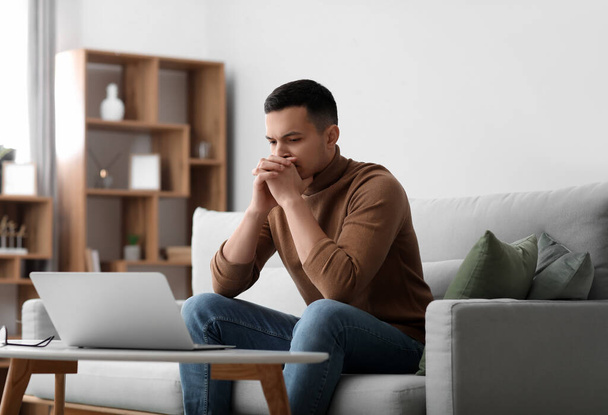 Problémový mladý muž sedící doma na pohovce - Fotografie, Obrázek