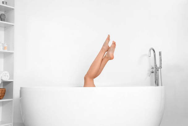 Босонога жінка у ванній біля світлої стіни
 - Фото, зображення