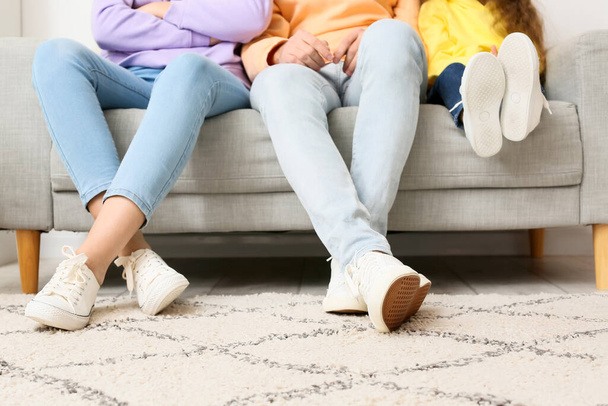 Молодая семья сидит дома на диване - Фото, изображение