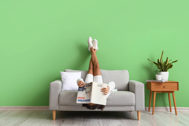 African-American teenage girl with magazine relaxing on sofa at home - Fotografie, Obrázek