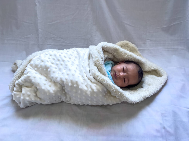 Sweet peaceful baby lying on a white bedsheet enjoy daytime nap - 写真・画像