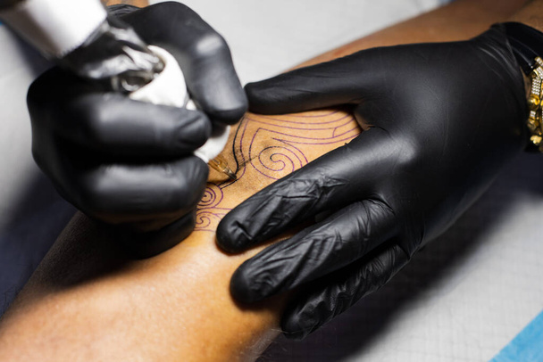 Tetoválóművész kezei fekete kesztyűben a tetoválószalonban..  - Fotó, kép