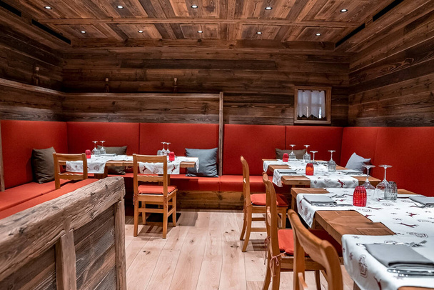 Tables and chairs arranged with sofas in hotel. Beautiful place setting at restaurant. Interior of rustic style dining hall in luxurious ski resort. - Photo, image