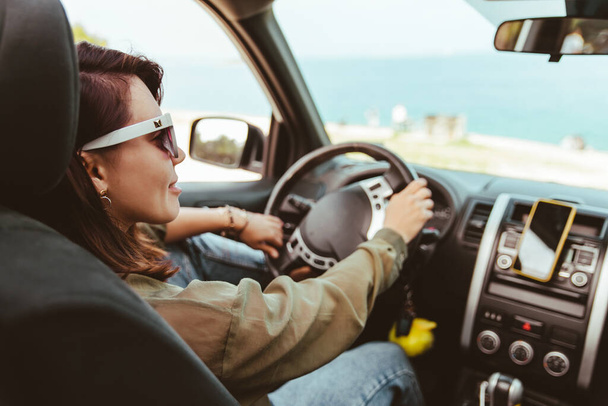 ontspannen stijlvolle vrouw in zonnebril rijden auto zee strand op de achtergrond, kopiëren ruimte - Foto, afbeelding