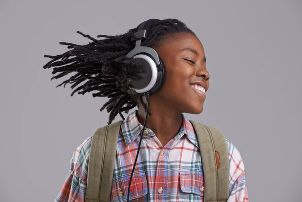 Pasando a vencer. Un chico afroamericano escuchando música por sus auriculares. - Foto, Imagen