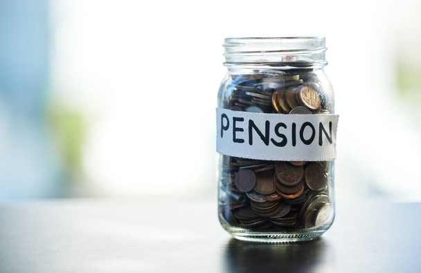 Save every dime and dollar. Shot of a pension money jar on a table at home. - Foto, Imagen