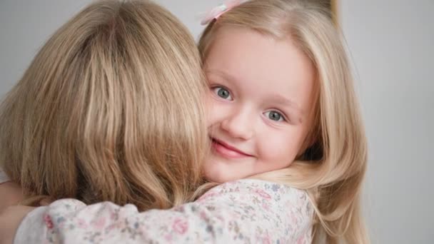 boldog család, imádnivaló mosolygós kislány szeretettel és gyengédséggel öleli szerető anyját, miközben otthon pihen - Felvétel, videó