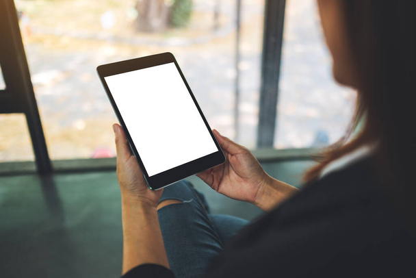 Imagen burlona de una empresaria sosteniendo una tableta negra con pantalla blanca en blanco en la oficina - Foto, Imagen