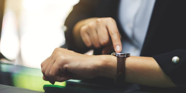 Una donna d'affari che indica un orologio da polso sul suo orario di lavoro in attesa di qualcuno in carica - Foto, immagini