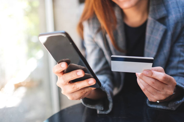 Closeup image of a woman using credit card for purchasing and shopping online on mobile phone - Photo, Image