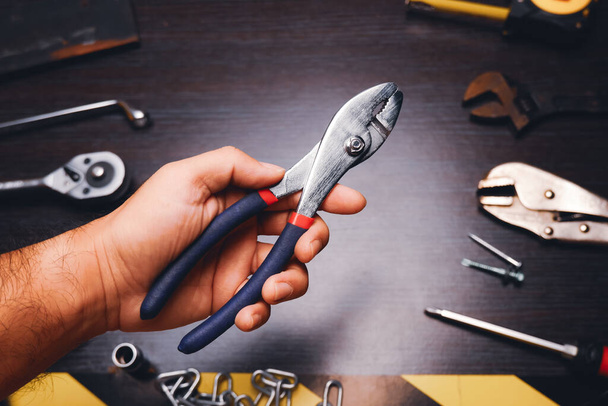 Metal pliers isolated on the mechanic hand with a mechanic tools background - Фото, изображение