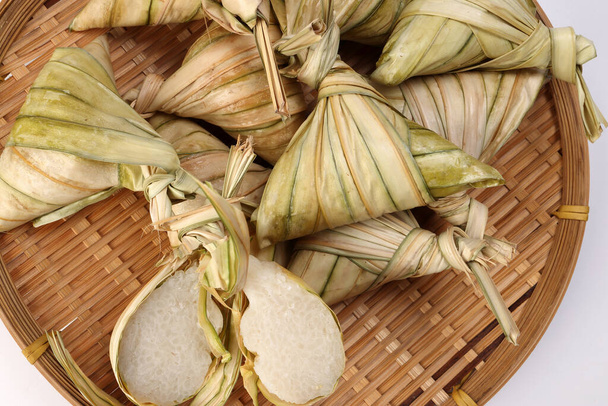 Tradicional bolso de hoja de palma tejida en forma de diamante al vapor glutenoso pastel de arroz ketupat kupat tipat en bandeja de bambú fondo blanco - Foto, imagen