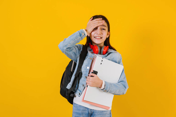 portrait of young hispanic child teen girl student with worried expression on a yellow background in Mexico Latin America - Photo, Image
