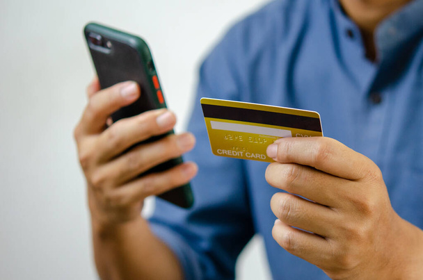 miehen hallussa luottokortti ja matkapuhelin verkkokaupoissa sähköinen kaupankäynti ja internet-pankkitoiminta. - Valokuva, kuva