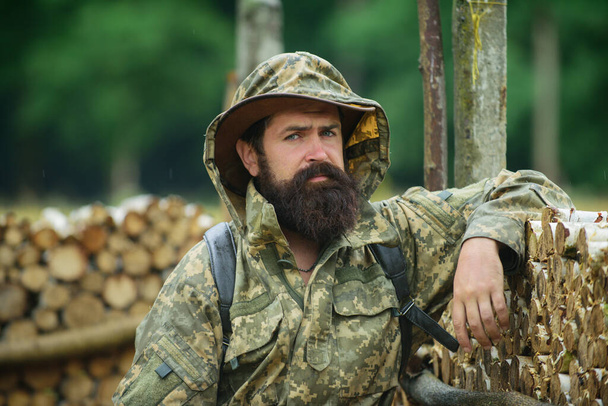 Portrait of adventure serious man extreme explorer. Man hunter in camouflage outdoor. Brutal hunter, bearded man in the wild forest in the autumn. Brutal village lifestyle. - Fotoğraf, Görsel