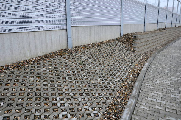 hiljattain perustettu katu kaupungissa, pitkittäinen pysäköintialue on valmistettu rei 'itetty betonin tunkeutumisen laatat puolella tietä hillitä. kaltevuuden vakauttaminen rivipalisadilla - Valokuva, kuva