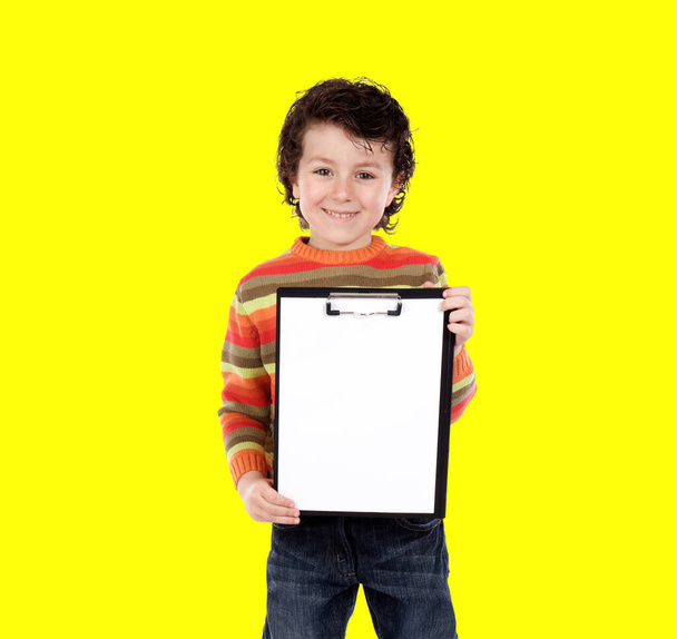 黄色の背景vに隔離されたクリップボードを持っている若い男の子 - 写真・画像