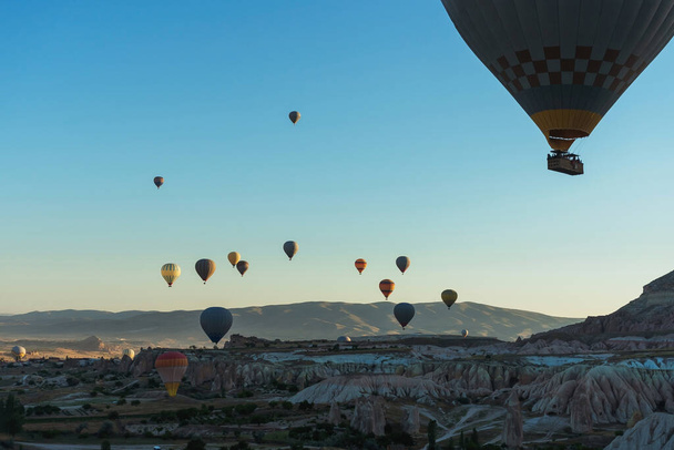 Palloncini sopra case di tufo in una valle in Cappadocia.Palloncini in cielo in Cappadocia in Turchia. Palloncini multicolori volanti colorati nel cielo - Foto, immagini