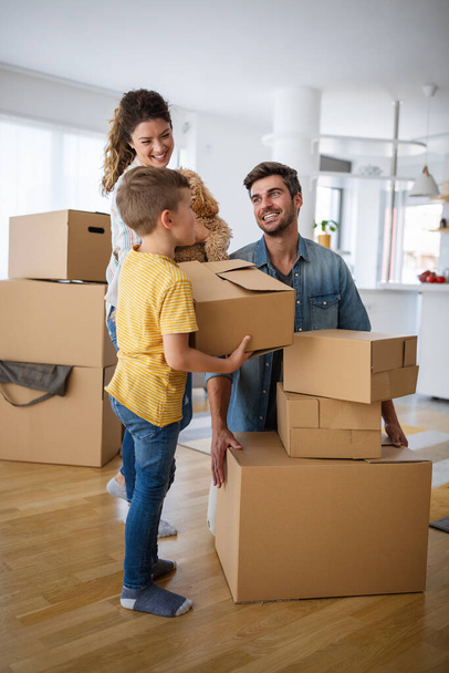 Happy young family unpacking cardboard boxes at new home. Moving in, new home people concept. - Foto, imagen
