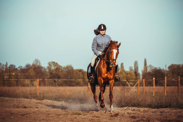 una hermosa joven montando un caballo en un casco negro y botas
 - Foto, Imagen