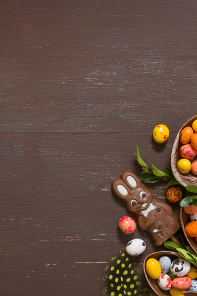 Easter hunt concept background with chocolate eggs and bunny on wooden table copy space. View from above - Photo, Image