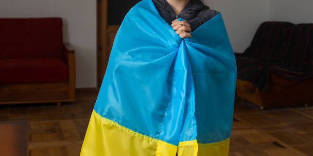 Маленькие девочки с украинским флагом перед стеной, разрушенной бомбами. Маленькие девочки машут национальным флагом, молясь о мире - Фото, изображение