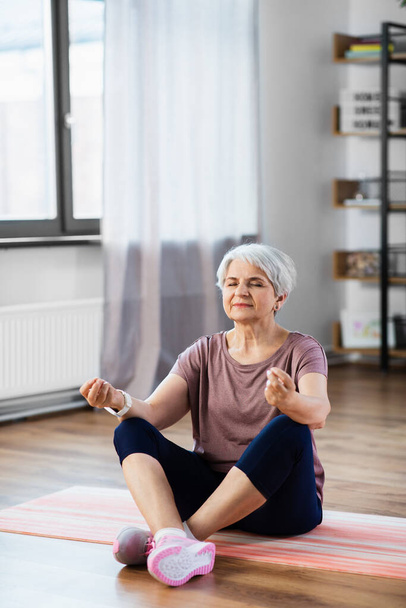 happy senior woman meditating on mat at home - Foto, imagen