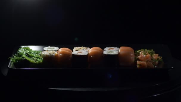 Sushi Rolls asetettu lohen kanssa mustalla tarjottimella - Materiaali, video