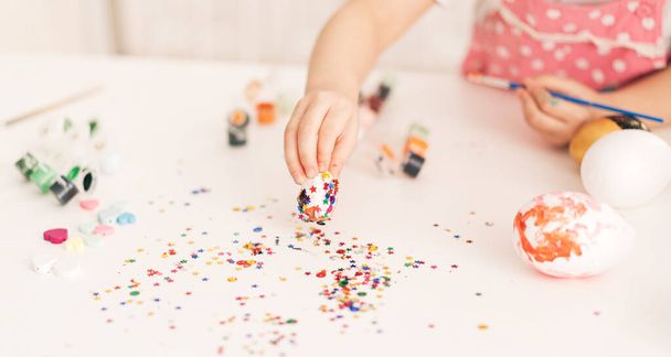 Little Child decorates Easter eggs with glitter - 写真・画像