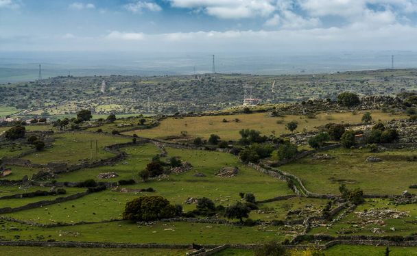 Een landschappelijk uitzicht op oude rotswanden en velden in het eikenlandschap van Extremadura - Foto, afbeelding