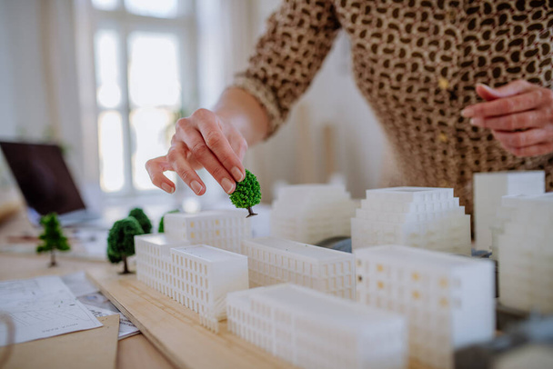 Close-up of woman architect with model of houses in office - 写真・画像