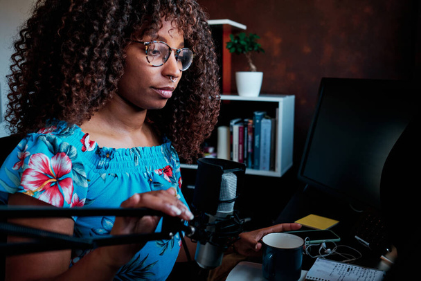 Fiatal göndör haj fekete nő podcasting mikrofonnal a számítógépen - Fotó, kép
