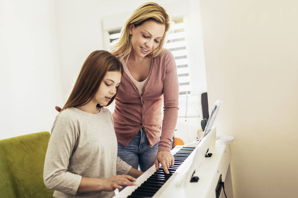 Music teacher shows how to play the piano. Girl learning play piano with teacher - Zdjęcie, obraz