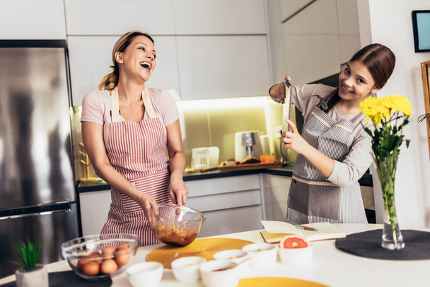 Sorridente madre e figlia che cucinano insieme in cucina
 - Foto, immagini