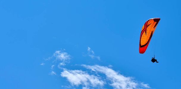 Gleitschirmflieger, der von einem Gipfel des Intelvi-Tals aus mit Blick auf die Schweizer Alpen und den Luganer See fliegt. Konzept von Lifestyle, Freiheit und Extremsportabenteuer. - Foto, Bild