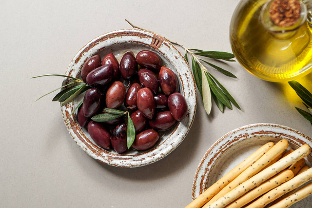 Kalamata olive, Aceitunas Kalamon and grissini breadsticks, olive oil. mediterranean snacks on the white modern style, top view - Photo, Image