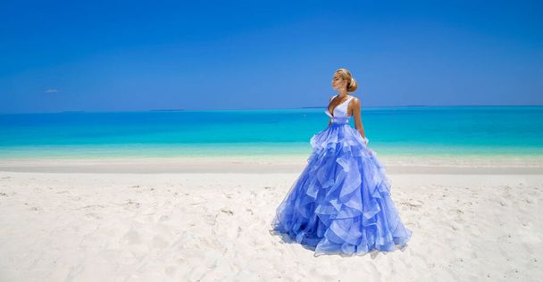 Розкішна мода. Виразна модель моди. Стильна жіноча модель в елегантній сукні з довгими сукнями на пляжі Мальдівів. Легенда. Наречена на Мальдівах. Невеличка мода. Класична жінка у дивовижній блакитній сукні. Мужність. - Фото, зображення