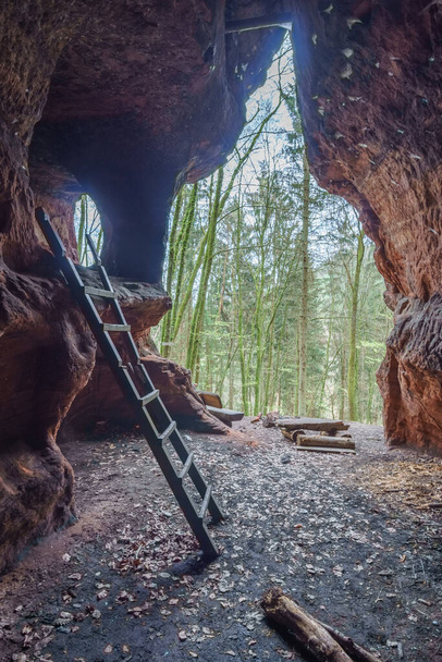 Antigua cueva de ladrones de arenisca roja con escalera de madera y vista al bosque cerca de Tréveris, Alemania - Foto, imagen